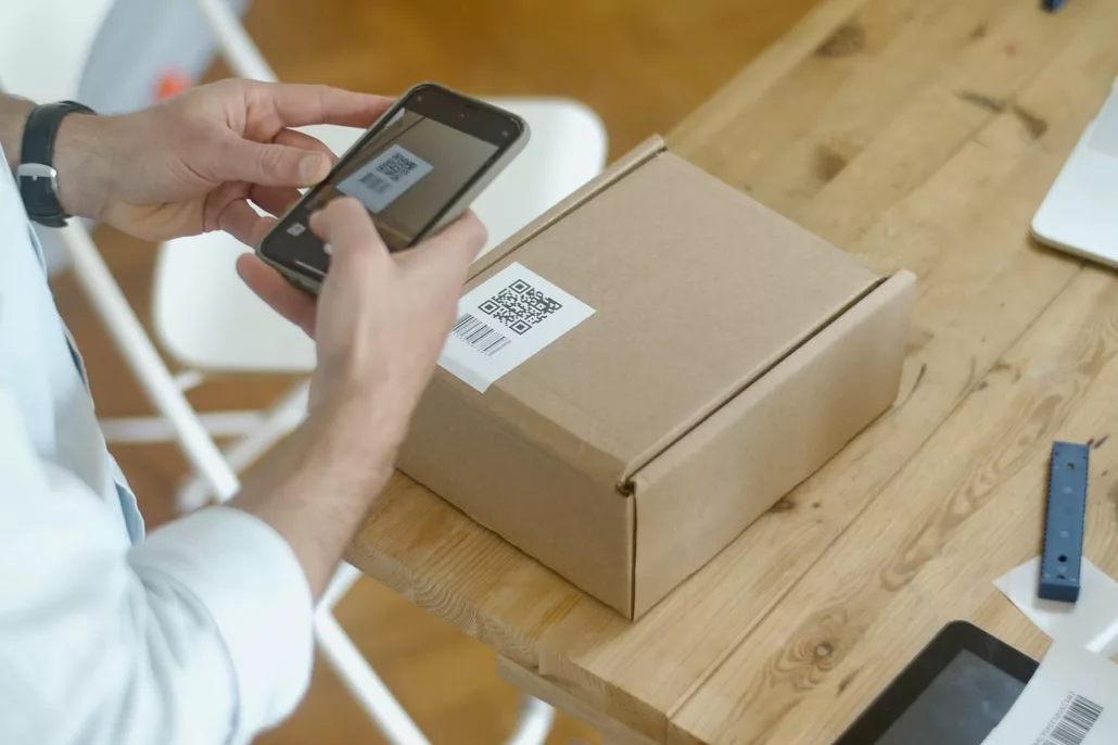 A person scanning a barcode on a box with their phone.